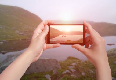 Norveç 'te gün batımında cep telefonuyla çekilmiş küçük bir göl resmi. Suleskard 'ın akıllı telefondaki kadın fotoğrafı.