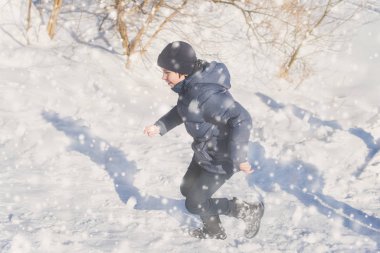 Parktaki genç çocuk Kışın kar yağarken. 