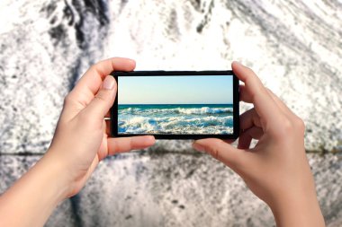 Kadın akıllı telefondan deniz fotoğrafı çekiyor. 