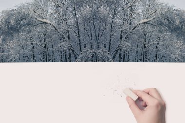 Female hand erased by eraser of winter landscape clipart