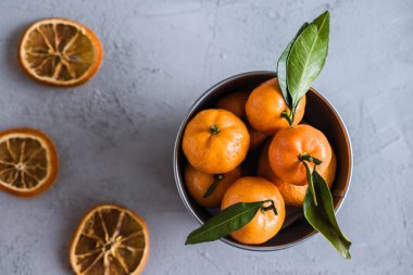 Gri beton arka plandaki küçük demir kovada Mandarinler