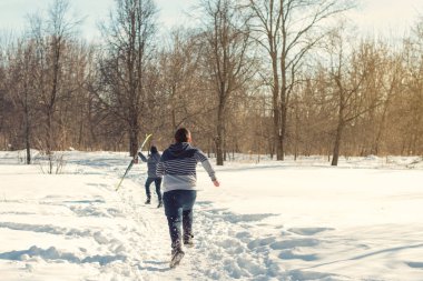 Kışın kar yağarken parkta kayak yapan gençlerin dikiz görüntüsü
