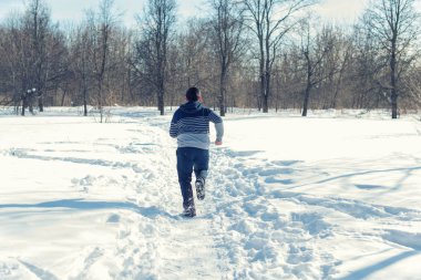 Karlı bir ormanda yol boyunca koşan bir çocuğun dikiz aynası. 