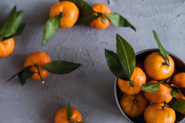 Gri beton arka plandaki küçük demir kovada Mandarinler