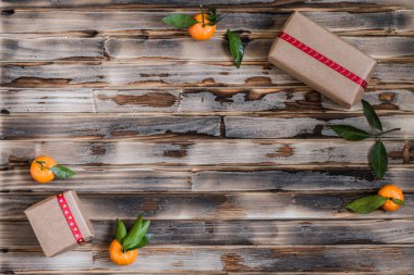 Mandalinaların Noel süslemesi, Noel ağacı, hediyeler ve kahverengi kırsal tahta arka planda parlak bir çelenk.