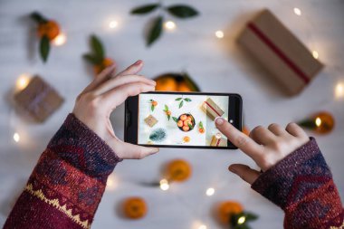 Cep telefonuyla fotoğraf çeken kadın blogcu. Mandalina süslemesi, Noel konsepti.