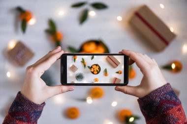 Cep telefonuyla fotoğraf çeken kadın blogcu. Mandalina süslemesi, Noel konsepti.