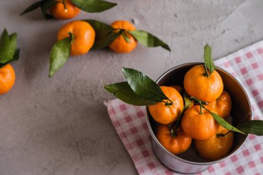 Gri beton arka plandaki küçük demir kovada Mandarinler