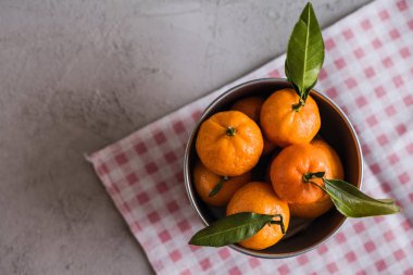 Gri beton arka plandaki küçük demir kovada Mandarinler
