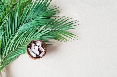 Hindistan cevizi büyük bir palmiye yaprağının üzerinde bir kasede dilimler kumsalın kumlarında