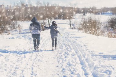 Kışın kar yağarken parkta kayak yapan gençlerin dikiz görüntüsü