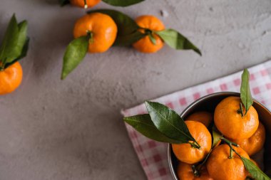 Gri beton arka plandaki küçük demir kovada Mandarinler