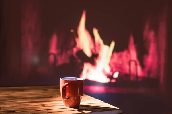 クリスマス暖炉の近くの木のテーブルの上で熱い飲み物のカップ いい雰囲気だまだ生きてる冬とクリスマスの休暇のコンセプト — ストック写真