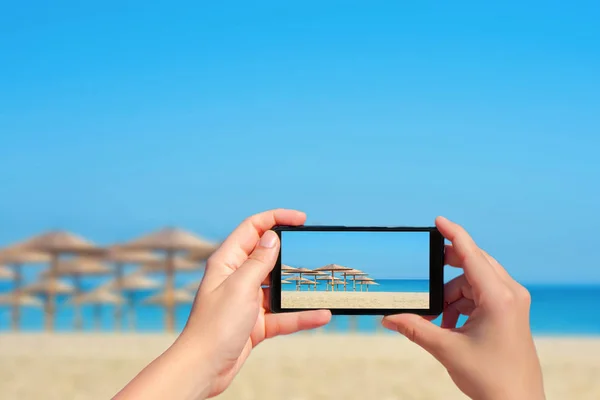 Жінка Фотографує Тропічний Пляж Великими Солом Яними Парасольками Мобільному Телефоні — стокове фото