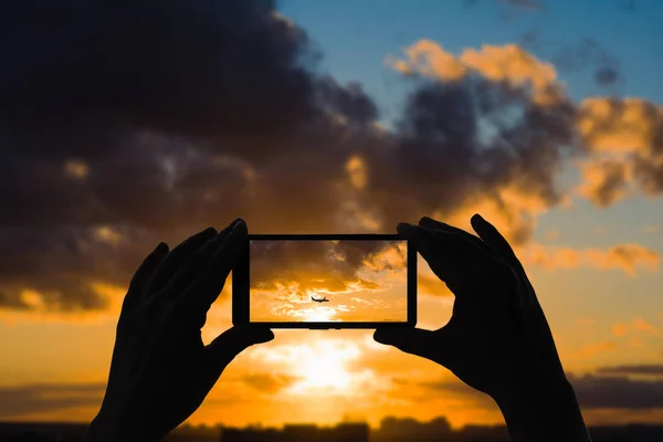 スマートフォンで日没後の飛行機の写真を撮る女性 — ストック写真