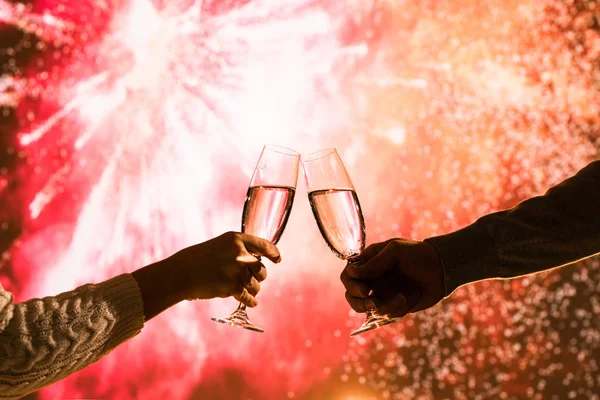 Merry man and woman toasting with glasses champagne celebrate holiday christmas or new year during celebratory fireworks on the  night sky.