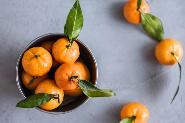 Gri beton arka plandaki küçük demir kovada Mandarinler