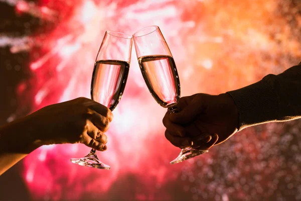 Merry man and woman toasting with glasses champagne celebrate holiday christmas or new year during celebratory fireworks on the  night sky.