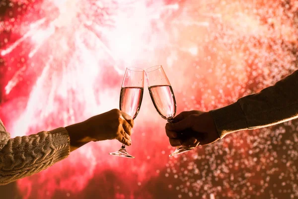 Merry man and woman toasting with glasses champagne celebrate holiday christmas or new year during celebratory fireworks on the  night sky.