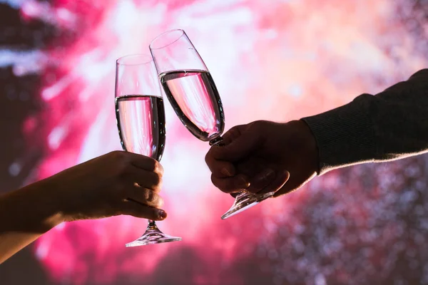 stock image Merry man and woman toasting with glasses champagne celebrate holiday christmas or new year during celebratory fireworks on the  night sky. 