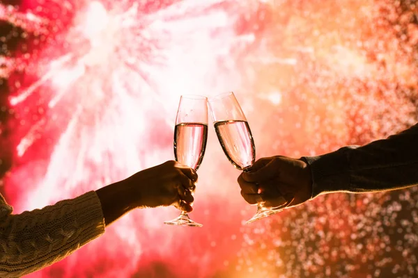 Merry man and woman toasting with glasses champagne celebrate holiday christmas or new year during celebratory fireworks on the  night sky.