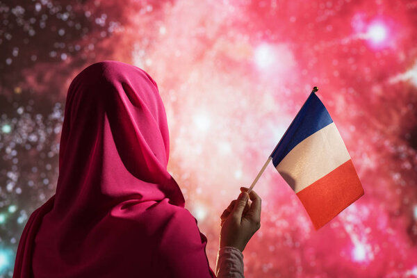 Muslim woman in a scarf holding flag of France during fireworks at night. — Stock Image Muslim Woman Scarf Holding Flag France Fireworks Night Royalty Free Stock Photos