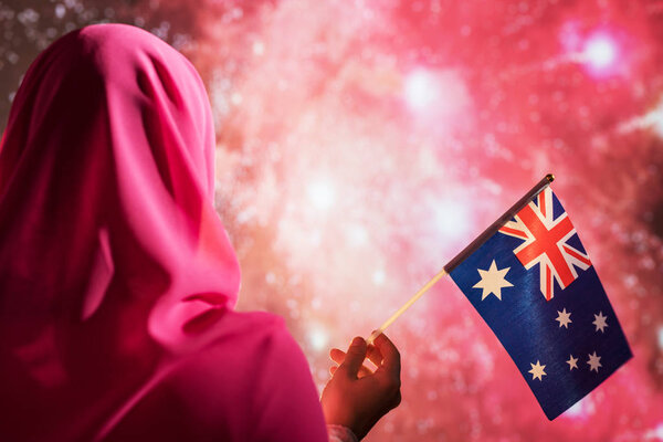 Muslim woman in a scarf holding Australian flag during fireworks at night. — Stock Image Muslim Woman Scarf Holding Australian Flag Fireworks Night Stock Photo