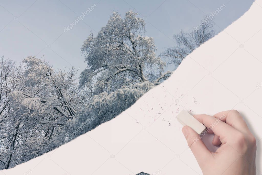 Female hand erased by eraser of winter landscape