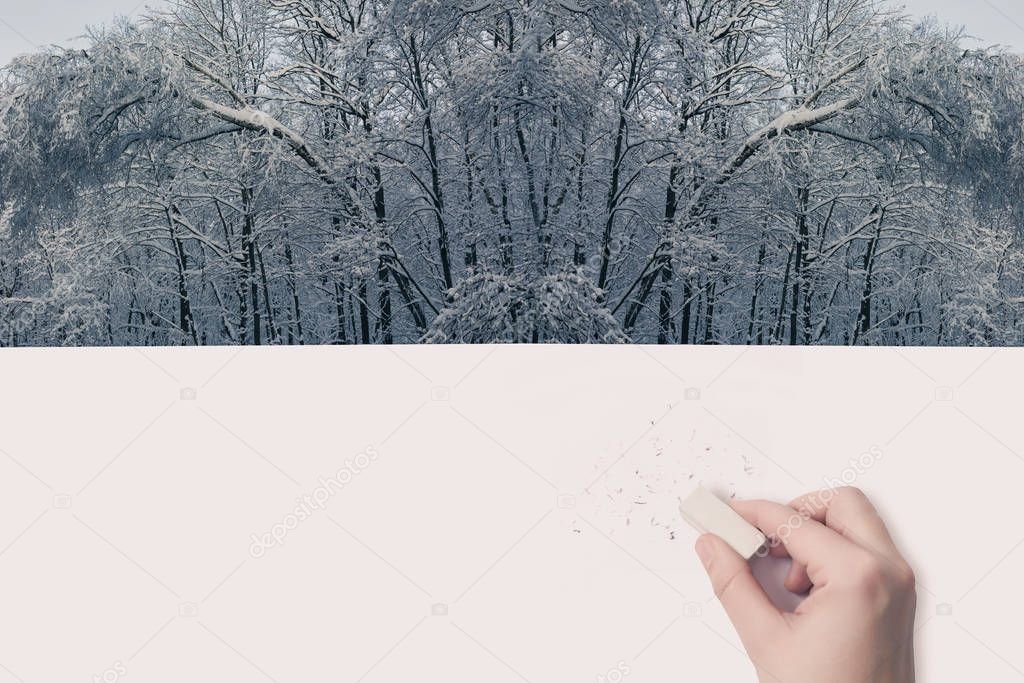 Female hand erased by eraser of winter landscape