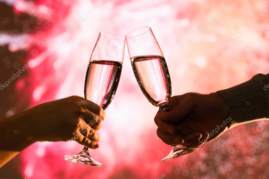 Merry man and woman toasting with glasses champagne celebrate holiday christmas or new year during celebratory fireworks on the  night sky. 