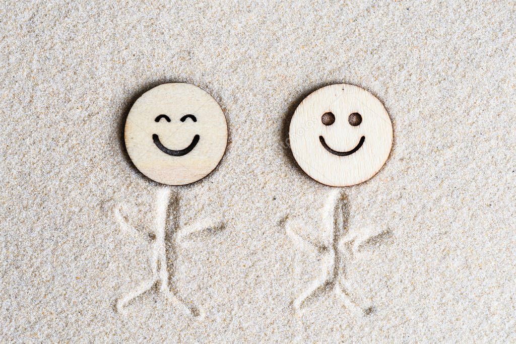 Two funny happy wooden smile face on the sand at the beach. Concept. Flat lay. Aerial view