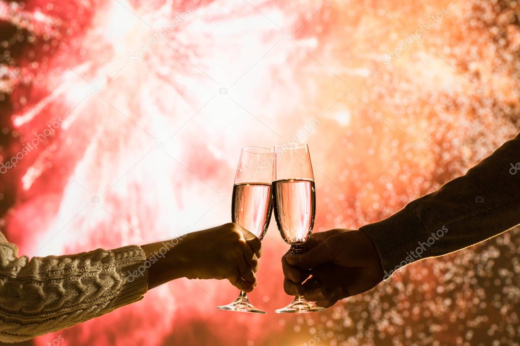 Merry man and woman toasting with glasses champagne celebrate holiday christmas or new year during celebratory fireworks on the  night sky. 