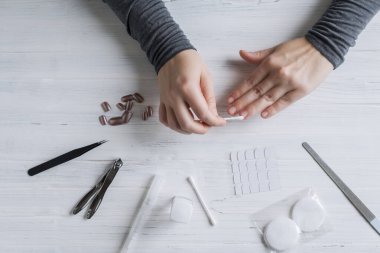 The process of putting artificial (fake) fingernail on the finger. Woman manicure. Flat lay.