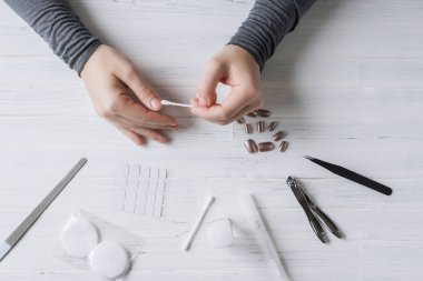 The process of putting artificial (fake) fingernail on the finger. Woman manicure. Flat lay.