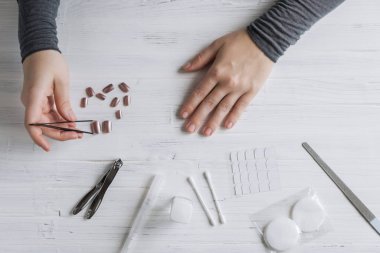 The process of putting artificial (fake) fingernail on the finger. Woman manicure. Flat lay.