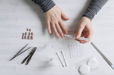 The process of putting artificial (fake) fingernail on the finger. Woman manicure. Flat lay.