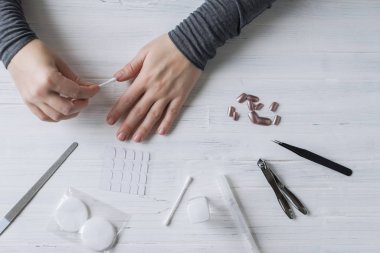The process of putting artificial (fake) fingernail on the finger. Woman manicure. Flat lay.