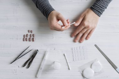 The process of putting artificial (fake) fingernail on the finger. Woman manicure. Flat lay.