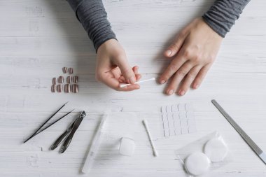 The process of putting artificial (fake) fingernail on the finger. Woman manicure. Flat lay.