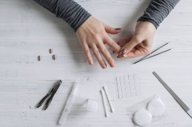 The process of putting artificial (fake) fingernail on the finger. Woman manicure. Flat lay.