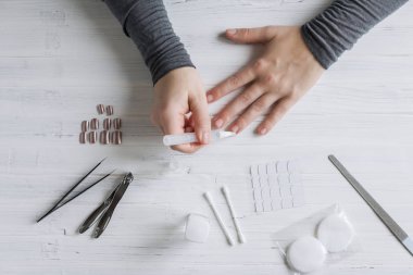 The process of putting artificial (fake) fingernail on the finger. Woman manicure. Flat lay.