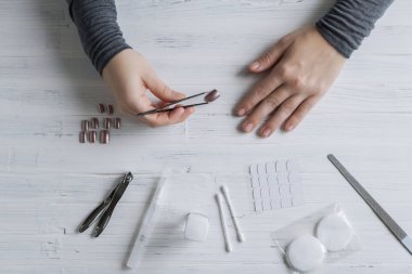 The process of putting artificial (fake) fingernail on the finger. Woman manicure. Flat lay.