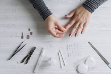 The process of putting artificial (fake) fingernail on the finger. Woman manicure. Flat lay.