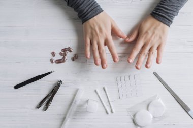 The process of putting artificial (fake) fingernail on the finger. Woman manicure. Flat lay.