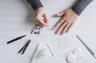 The process of putting artificial (fake) fingernail on the finger. Woman manicure. Flat lay.