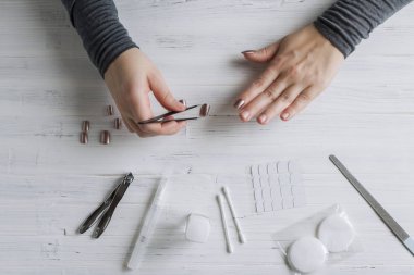 The process of putting artificial (fake) fingernail on the finger. Woman manicure. Flat lay.