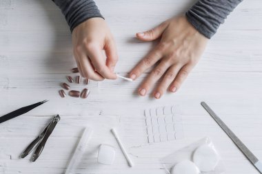 The process of putting artificial (fake) fingernail on the finger. Woman manicure. Flat lay.