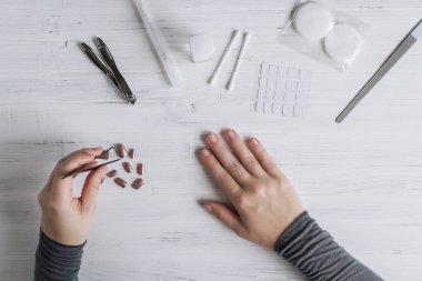 The process of putting artificial (fake) fingernail on the finger. Woman manicure. Flat lay.