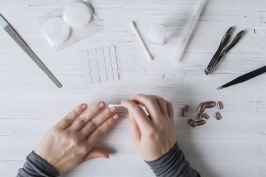 The process of putting artificial (fake) fingernail on the finger. Woman manicure. Flat lay.