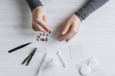 The process of putting artificial (fake) fingernail on the finger. Woman manicure. Flat lay.